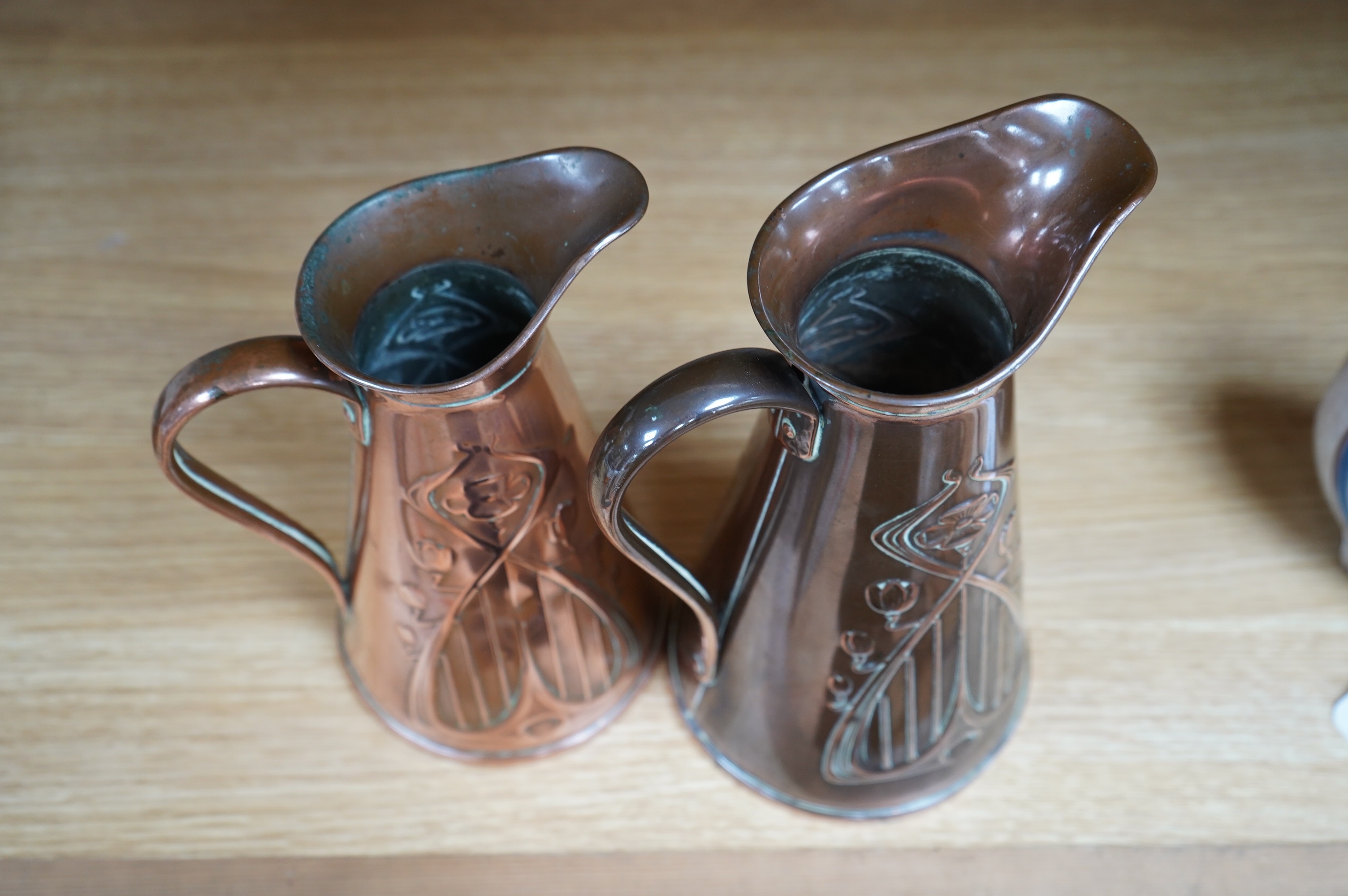 Two Joseph Sankey Art Nouveau embossed copper jugs, tallest 23cm. Condition- fair to good